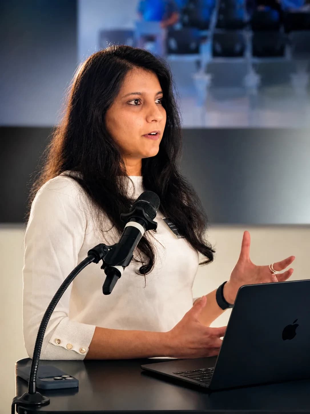 Sonali speaking into a microphone at a lectern